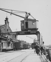 Eine historische Aufnahme des Oldenburger Hafens mit einem imposanten Hafenkran und Lagergebäuden. Dieses Bild zeigt die industrielle Vergangenheit der Stadt und die Verbindung zum wirtschaftlichen Zentrum.