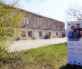 Zweistöckiges Gebäude aus Backsteinen. Davor steht ein Werbeaufsteller der WBS TRAINING.