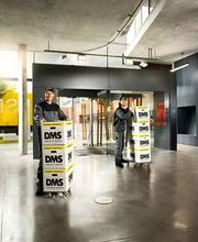 Mitarbeitende transportieren DMS-Umzugskartons durch ein Gebäude
