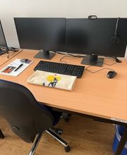 Arbeitsplatz bestehend aus 2 PC-Bildschirmen, Tastatur, Maus und Headset sowie einem Bürostuhl.