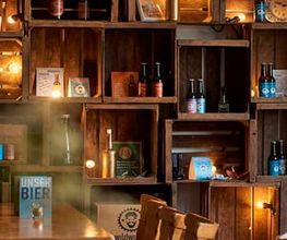 Der gemütliche Ausschankraum der Wildwuchs Brauerei in Hamburg überzeugt mit rustikalem Charme und liebevollen Details. Warme Lichtquellen, alte Holzkisten und handgebraute Biere schaffen eine authentische Atmosphäre, die zum Verweilen einlädt.