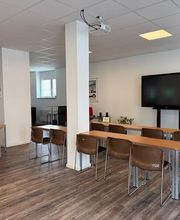 Academy Fahrschule Baumann - Stuttgart Vaihingen - Heller Schulungsraum für Theorieunterricht in Stuttgart-Vaihingen mit Tischen, Stühlen, Bildschirm und moderner Ausstattung zur Prüfungsvorbereitung.