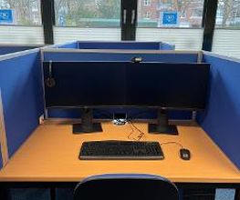 Ein Arbeitsplatz mit Fenstersicht. Auf dem Tisch stehen zwei Monitore, eine Tastatur und eine Maus. Unter dem Tisch befindet sich ein Computer.