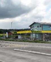 AGROLA Tankstelle in Buttisholz mit TopShop und Landi; im Vordergrund Strasse mit Fussgängerstreifen, links Totem mit Landi Schild, AGROLA Schild, digitaler Preisanzeige Treibstoff, selfwash dach 