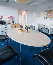 Tisch in einem Pausenraum mit mehreren Stühlen und Blumen auf dem Tisch.