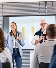 Ein professionell ausgestatteter Konferenzraum in der Alten Stadtkasse Oldenburg, der sich ideal für Schulungen, Vorträge und Präsentationen eignet. Auf dem Bild halten zwei Vortragende eine Präsentation vor einem aufmerksamen Publikum. Der Raum ist mit moderner Präsentationstechnik und komfortablen Sitzmöglichkeiten ausgestattet.