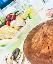 Ein gedeckter Tisch mit Kuchen, Donuts, Baguette und Obst.