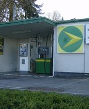 AGROLA Tankstelle in Pfäffikon, Schwyz. Grosses AGROLA Logo an Fassade, rechts daneben digitale Preisanzeige. Eine Tanksäule und ein Zahlterminal.