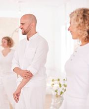 Freundliche Kurssituation mit Yogalehrer und Teilnehmenden im hellen Studio. Das Bild zeigt die persönliche und offene Atmosphäre bei KarmaConcepts.