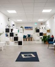 Foyer mit Sitzgelegenheiten, weißen Regalen und einem Fußläufer mit WBS TRAINING Logo. 