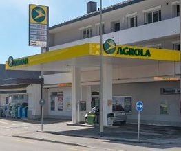 AGROLA Tankstelle in Hausen am Albis. Überdacht mit einer Tanksäule. Dach an Gebäudewand angebracht. Schild mit Pfeil zur Einfahrtsanzeige