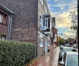 Der Fußweg vor dem Gebäude an einer Hecke