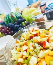 Bild von einem gedeckten Tisch mit Obststalat, einem Obstkorb sowie verschiedenen Aufstrichen und Baguette.