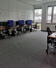 Arbeitsplätze bestehend aus 2 PC-Bildschirmen, Tastatur, Maus und Headset sowie einem blauen Bürostuhl und blauen Trennwänden.