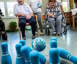Das Bild zeigt eine fröhliche Szene in einem Gemeinschaftsraum eines Seniorenheims.