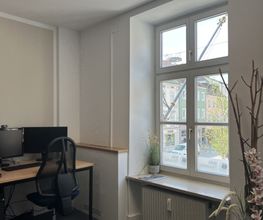 Schulungsraum mit Fenster rechts. Links ein Arbeitsplatz mit 2 Bildschirmen, einem Bürostuhl, Tastatur und Maus.