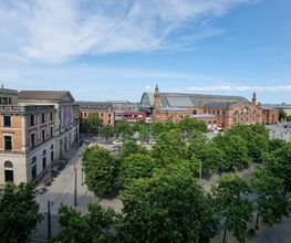 Blick aus dem Fenster auf das Bahnhofsgelände mit einem schönen, großen Gebäude.