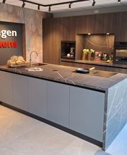 Warme eilandkeuken met hoge kastenwand in houtdecor.
