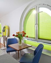 Hellgrünes leuchtendes Plissee im Verkaufsraum einfarbig im halbrunden Fenster. Farbige Plissees und Jalousien als Sichtschutz sind besser als Gardinen oder Vorhänge. Passen in jede Fensterform. Perfekt für Fensterbogen. Wurzbach, Bad Lobenstein, Saale-Orla kreis, Kronach, Coburg, Oberfranken und Umgebung