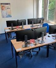 mehrere PC-Arbeitsplätze mit Monitoren, Tastatur, Maus und Headset.