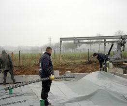 Das Team von AS-Bau verlegt Stahlprofile auf der Folie der Bodenplatte eines Neubaus.