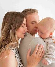 Kara Elizabeth Photography Familienfotografie in München – Eltern halten ihr Baby liebevoll im Arm. Einfühlsame Homestory mit echten Emotionen.