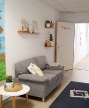 Gemütlicher Wartebereich in dem eine graue Couch mit einem kleinem weißen Tisch steht.