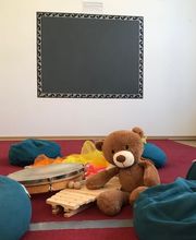 Gruppenraum mit Sitzkissen, Teddybär und Musikinstrumenten für kreative Kinderstunden - Luft(T)raum Leipzig