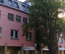 Außenansicht vom Gebäude an einer Straße. Rote Fassade und WBS TRAINING Schild. 