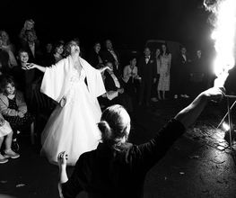 Hochzeitsfotograf Tom Maiwald - Momentaufnahme einer Hochzeitsfeier mit Braut und Feuerkünstler. Authentische Hochzeitsreportage mit spontanen Reaktionen, Gästen und außergewöhnlicher Abendunterhaltung.