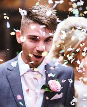 Gäste werfen Blütenblätter auf das glückliche Brautpaar nach ihrer Freien Trauung.