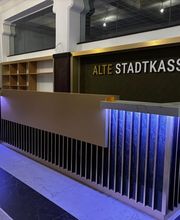 Der modern gestaltete Empfangsbereich der Alten Stadtkasse in Oldenburg beeindruckt mit einer stilvollen Kombination aus goldenen und dunklen Akzenten sowie einer beleuchteten Theke. Dieser einladende Raum ist der zentrale Punkt für Besucher, sei es für Meetings, Veranstaltungen oder Coworking.