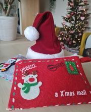 Eine Rote Nikolausmütze und ein roter Stoffumschlag mit der Aufschrift "Urgent - A X'mas mail"