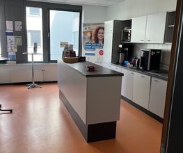 Moderne Küche mit Kaffeemaschine und Mikrowelle sowie einer Theke und Stehtischen. Pausenraum.