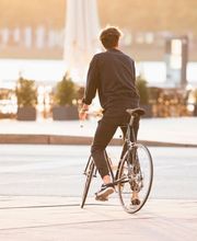 Ein Mann fährt in der warmen Abendsonne durch die Hamburger Hafencity. Das Bild vermittelt Freiheit, Leichtigkeit und urbanen Lifestyle im goldenen Licht des Sonnenuntergangs.