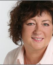 Eine Frau mit mittellangen brünetten Haaren und heller Bluse.