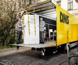 Zwei Mitarbeiter verladen ein verpacktes Möbelstück in einen DMS LKW