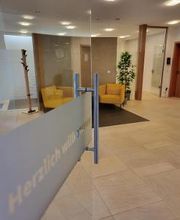 Eingangstür mit Blick in den Empfangsraum in dem 2 gelbe Sessel stehen. 