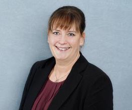 Eine Frau mit schwarzem Blazer und Bordeauxroter Bluse.