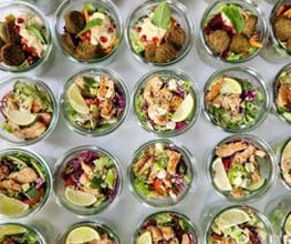 dean&david Catering | Pforzheim - Frische Salate im Glas mit Falafel, Hummus, Minze, Granatapfel und knackigem Gemüse neben Chicken Bowls mit Limette für vielseitiges Event Catering.