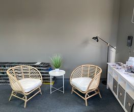 Kleine Sitzecke bestehen aus 2 Stühlen und einem kleinen Beistelltisch. Sowie einer modernen Stehlampe im Hintergrund und einem weißen Regal.