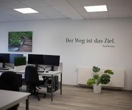 Ein Schulungsraum mit PC-Arbeitsplätzen. An der Wand befindet sich ein Bild und ein Wandtattoo mit der Aufschrift "Der Weg ist das Ziel. -Konfuzius"