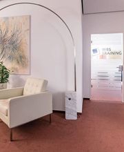 Gemütliche Sitzecke mit 2 großen, weißen Sesseln und einer modernen Stehlampe. An der Wand hängt ein kunstvolles Bild.