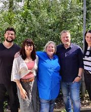 Ein Gruppenfoto vom Standortteam bestehend aus 3 Frauen und 2 Männern. Die Personen stehen draußen im Grünen.