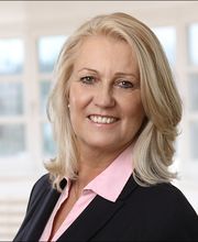 Eine Frau mit mittellangen hellen Haaren, schwarzem Blazer und rosa Bluse.