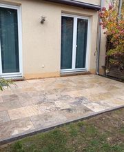 Neu gestaltete Terrasse von Krippner, Garten- und Landschaftsbau bei Berlin mit großformatigen Natursteinplatten in warmen Beige und Brauntönen. Die gepflasterte Fläche verbindet das Wohnhaus harmonisch mit dem Garten und bietet ausreichend Platz für einen gemütlichen Sitzbereich.