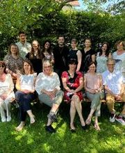 Eine Gruppe von mehreren Frauen und Männern posiert für ein Foto in einem Garten.