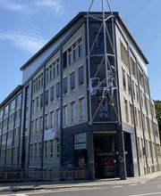 Außenansicht des Gebäudes in Leipzig Süd. Eckgebäude mit einem kunstvollen Gestell auf dem eine Figur angebracht ist.