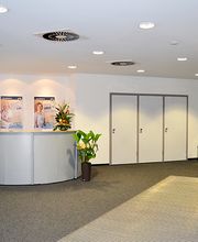 Heller Eingangsbereich mit Empfang und mehreren Zimmerpflanzen. 