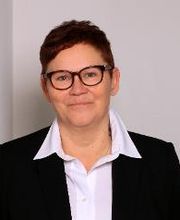 Portrait der Teamassistentin Claudi Michel. Eine Frau mit kurzen, braunen Haaren und Brille, die freundlich in die Kamera schaut.